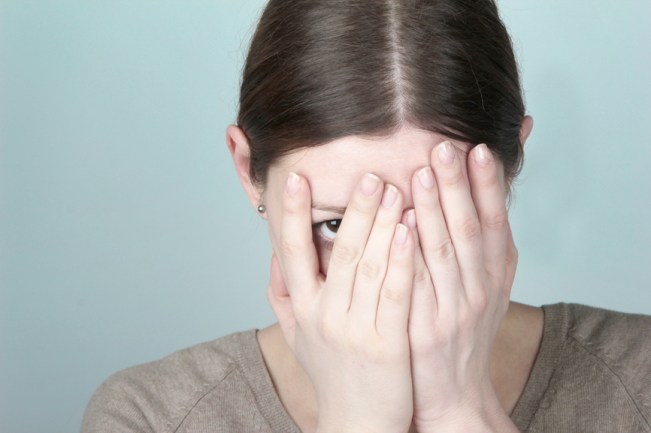 Photo of woman hiding behind her hands